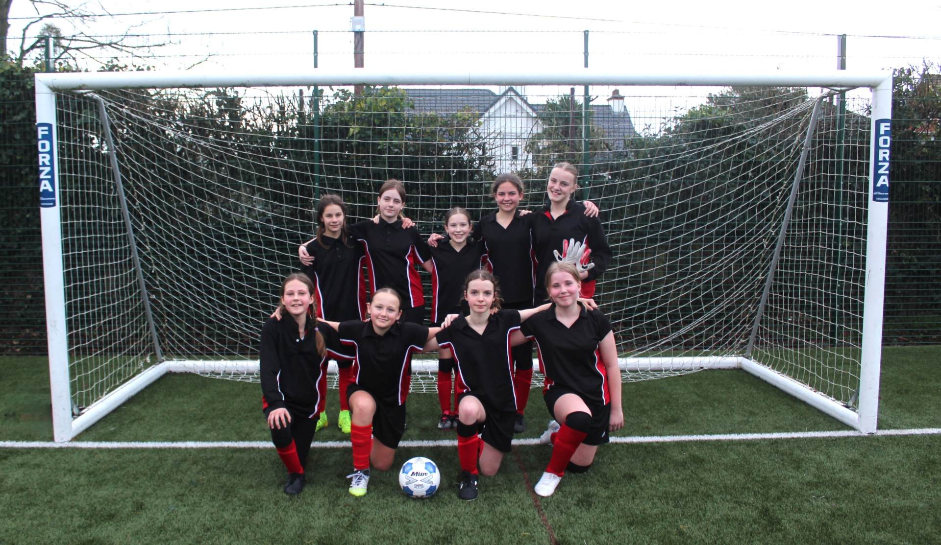 Year 7 football team posing for a photo infront of the goal