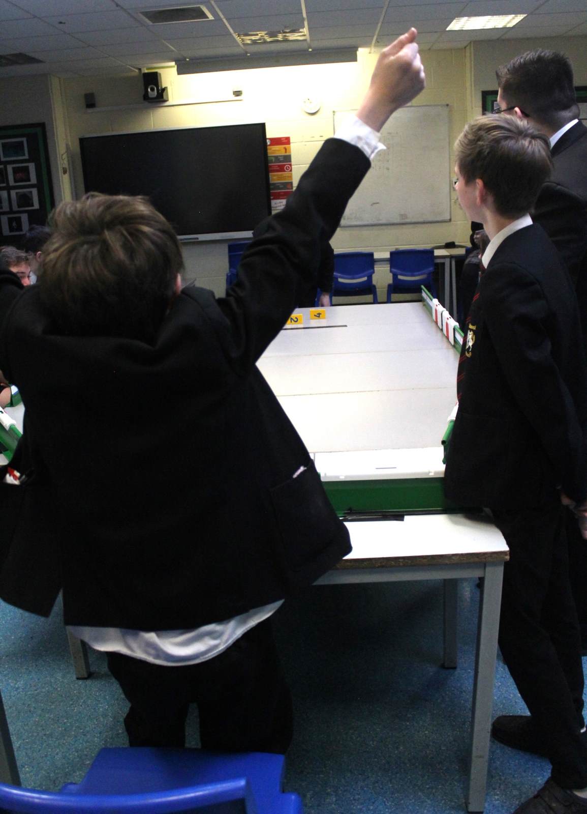 Students playing table top cricket and celebrating the win